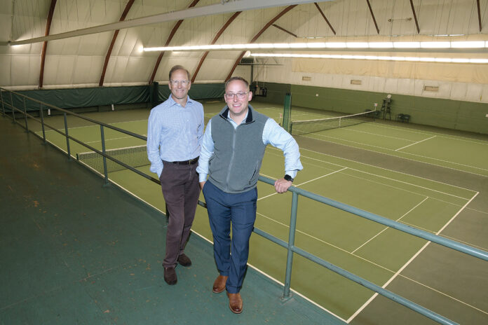 COURTING MEMBERS: Lance Pryor, left, owner and member of Agawam Hunt’s management team, and Joshua Helm, assistant general manager and controller, are pictured at the club’s indoor tennis courts. Pryor said golf “as the sole value proposition” is a challenging one right now.  / PBN PHOTO/MIKE SKORSKI