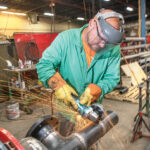 Thanks to digital imaging, more work for construction projects can be done in house. In this case Arden Building pipefitter/welder Andy Guimond can weld and grind 30 of the 40 connections needed for this pipe at the company’s Pawtucket facility before taking the piece to the building site. / PBN PHOTO/DAVE HANSEN