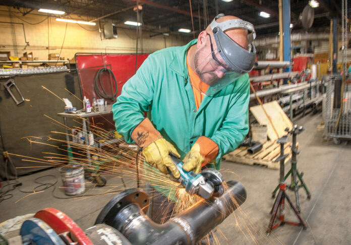 Thanks to digital imaging, more work for construction projects can be done in house. In this case Arden Building pipefitter/welder Andy Guimond can weld and grind 30 of the 40 connections needed for this pipe at the company’s Pawtucket facility before taking the piece to the building site. / PBN PHOTO/DAVE HANSEN