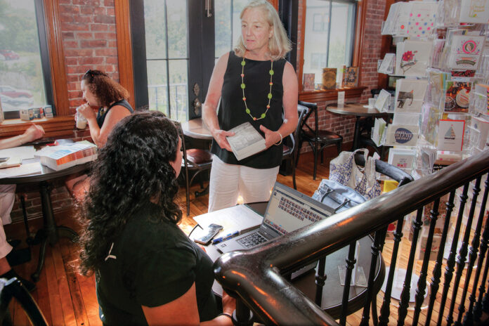 BUY LOCAL: Annie Philbrick, standing, owner of Savoy Bookshop & Café in Westerly, visits with customers in 2017. The shop is one of many Rhode Island businesses hoping shoppers buy local this holiday season. / PBN FILE PHOTO/BRIAN MCDONALD BUY LOCAL: Annie Philbrick, standing, owner of Savoy Bookshop & Café in Westerly, visits with customers in 2017. The shop is one of many Rhode Island businesses hoping shoppers buy local this holiday season. / PBN FILE PHOTO/BRIAN MCDONALD