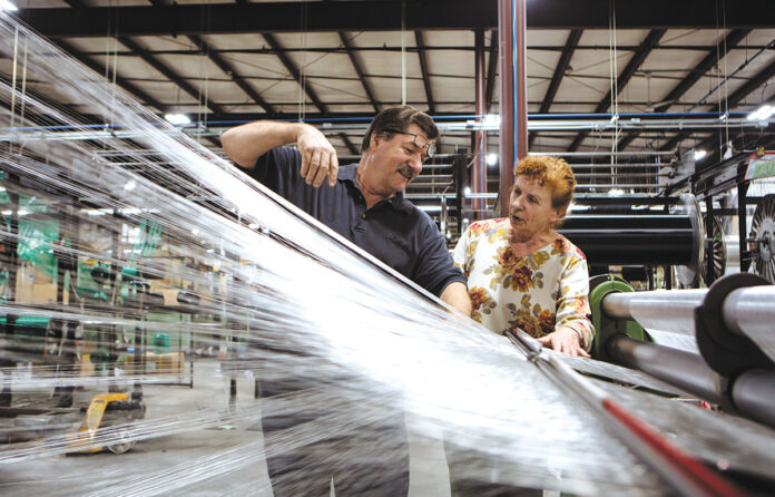 COMMON THREADS: Longtime American Cord & Webbing Co. employees Joseph and Grace Fura monitor a weaving machine at the company’s facility in Woonsocket. / PBN PHOTO/RUPERT WHITELEY