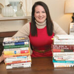 MORE AFFORDABILITY: Rhode Island Association of Realtors President Shannon Buss, bracketed by books that have been key to her real estate career, says three consecutive interest-rate cuts by the Fed haven’t led to new homebuyers entering the market, but they have helped buyers who are already looking to afford more in a house. / PBN PHOTO/MICHAEL SALERNO