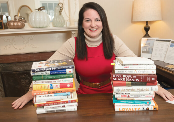 MORE AFFORDABILITY: Rhode Island Association of Realtors President Shannon Buss, bracketed by books that have been key to her real estate career, says three consecutive interest-rate cuts by the Fed haven’t led to new homebuyers entering the market, but they have helped buyers who are already looking to afford more in a house. / PBN PHOTO/MICHAEL SALERNO