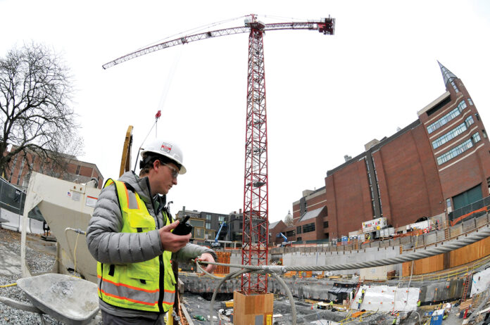 AIMING HIGH: A worker from Shawmut Design and Construction communicates with colleagues at the site of the new Brown University Performing Arts Center on College Hill in Providence. The tower crane is being used in the construction of the building, which is being overseen by Shawmut. / PBN PHOTO/MIKE SKORSKI