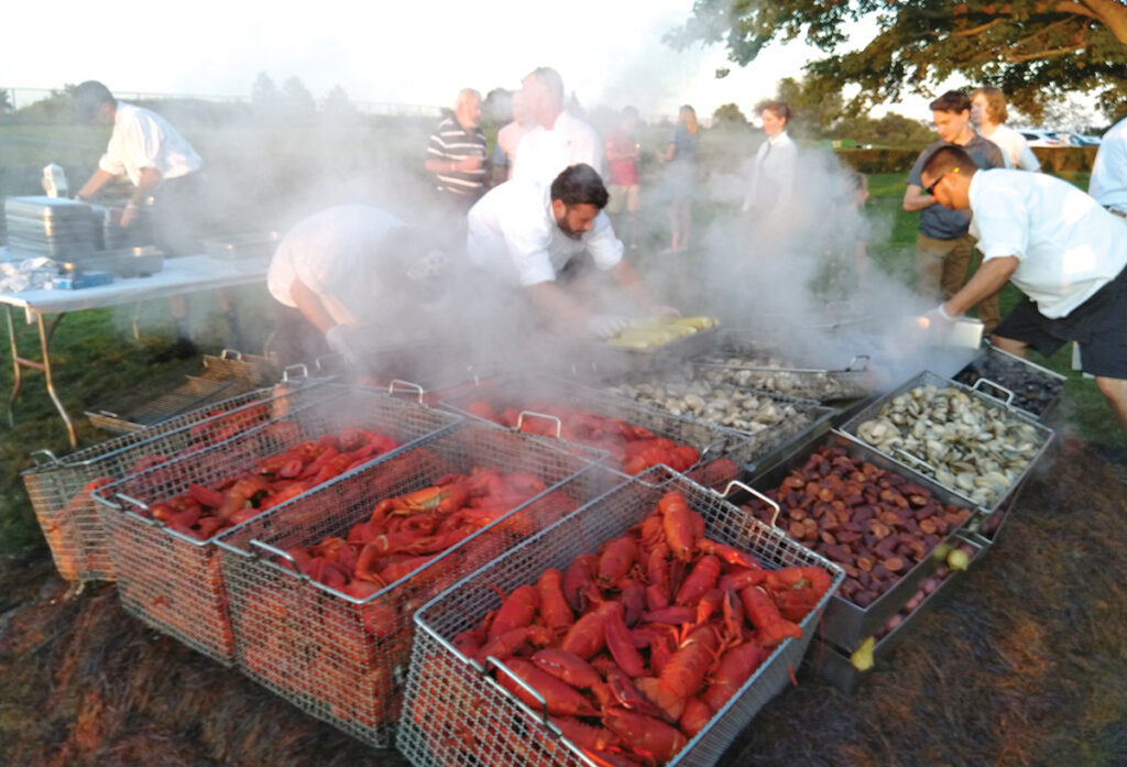 SEA OF FOOD CHOICES: Lobster and other items are prepared at a clambake this past summer in Newport. Seafood has long been a specialty in Rhode Island, but other areas of the food industry have made recent strides in the Ocean State.   / COURTESY MCGRATH CLAMBAKES INC.